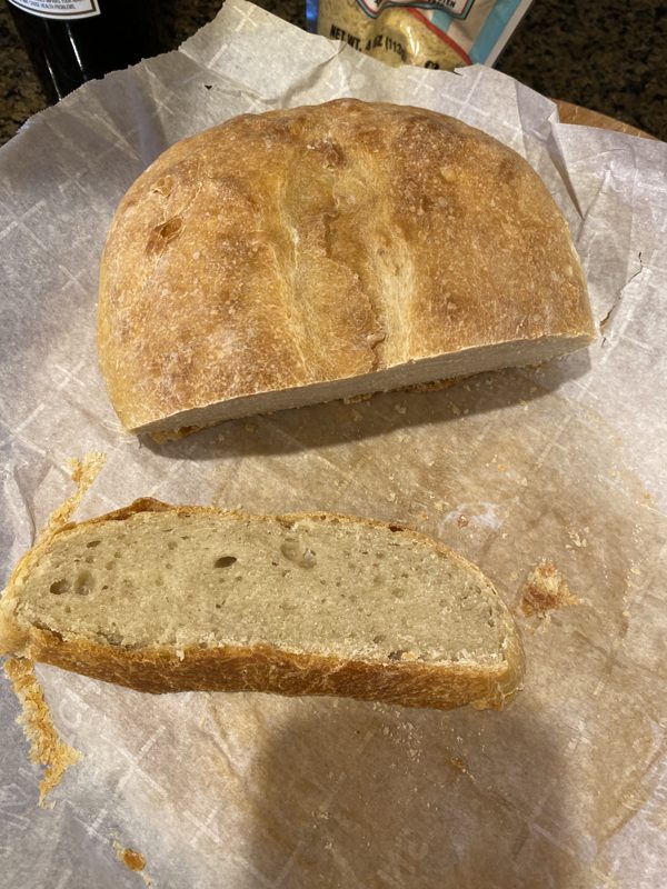 A pale golden loaf on parchment with one thick slice cut from it